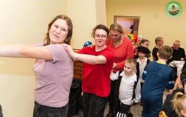 Uczestnicy Karnabalu podczas zabawy tworzą &lsquo;&rsquo;pociąg&rsquo;&rsquo;, przy stole widać kolejne, rozmawiające osoby.