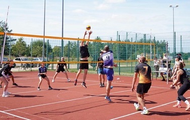 Zawodnicy podczas sportowej rywalizacji na boisku do piłki siatkowej.